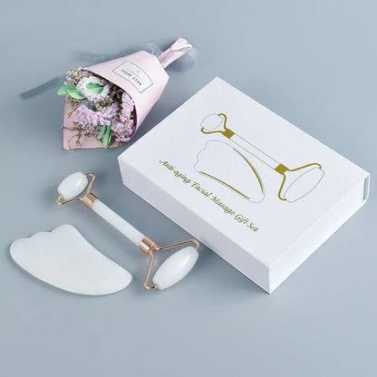 White jade facial roller with double-headed claw design and matching scraping board on dark surface