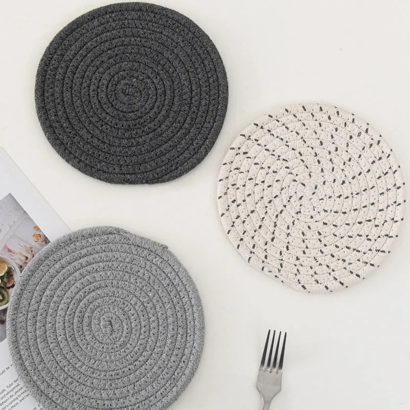 Three round grey cotton cord coaster placemats on a wooden table, each 18cm in diameter.