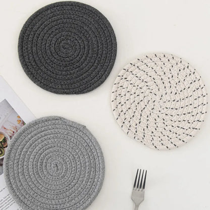 Three round grey cotton cord coaster placemats on a wooden table, each 18cm in diameter.