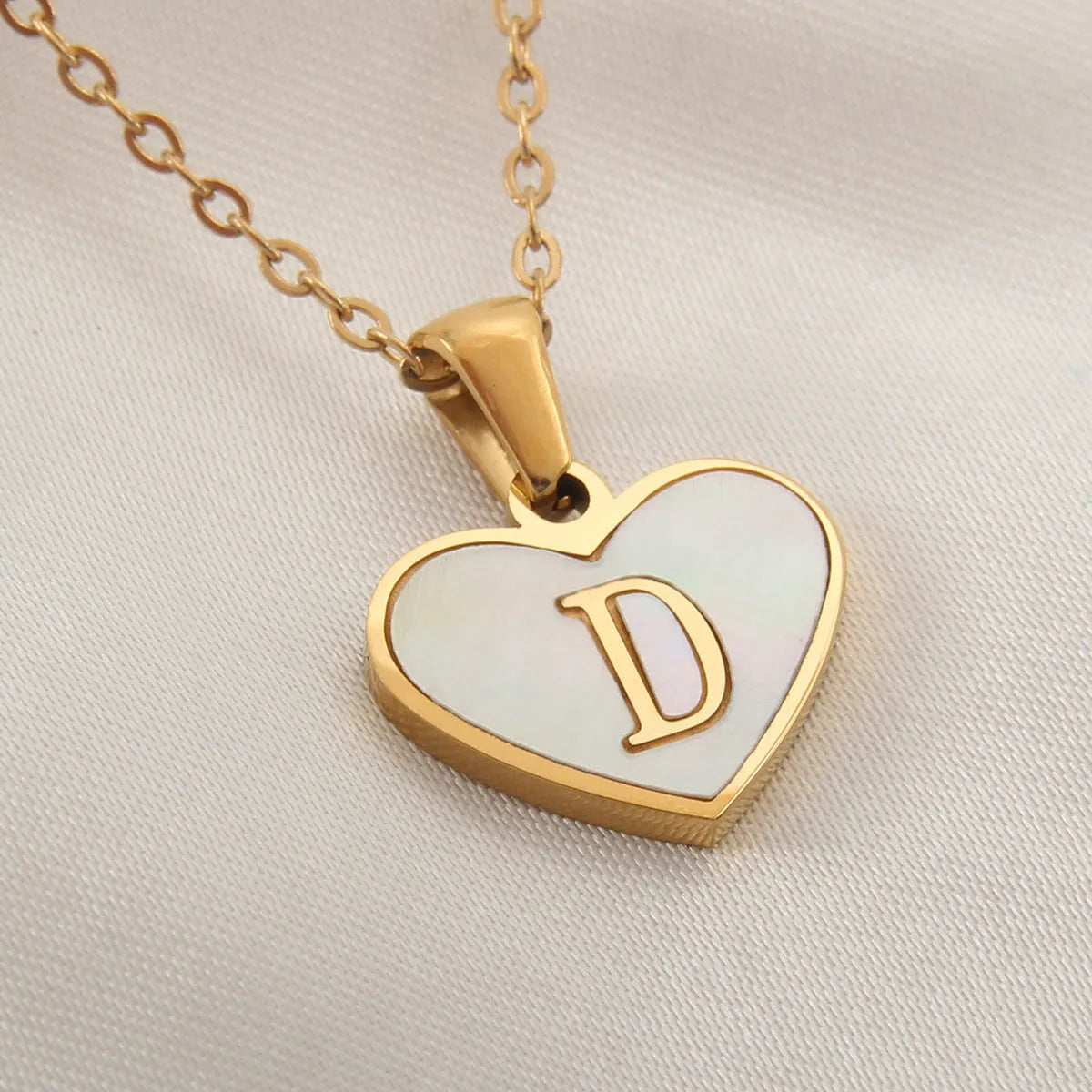 Gold-plated heart necklace with white shell pendant showing letter personalisation option