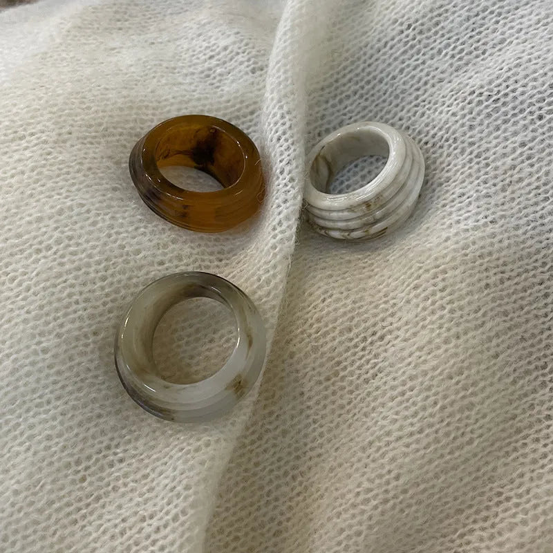 Geometric Chinese-style wide resin ring in brown and white colours on a plain background.
