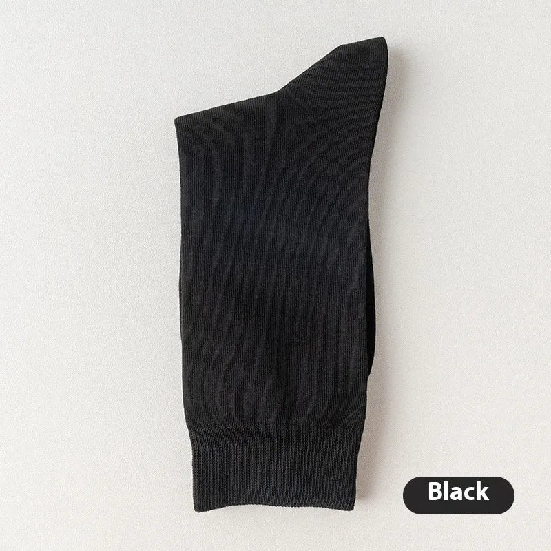 Pair of solid-colour men's mid-calf socks made from combed cotton on a wooden background