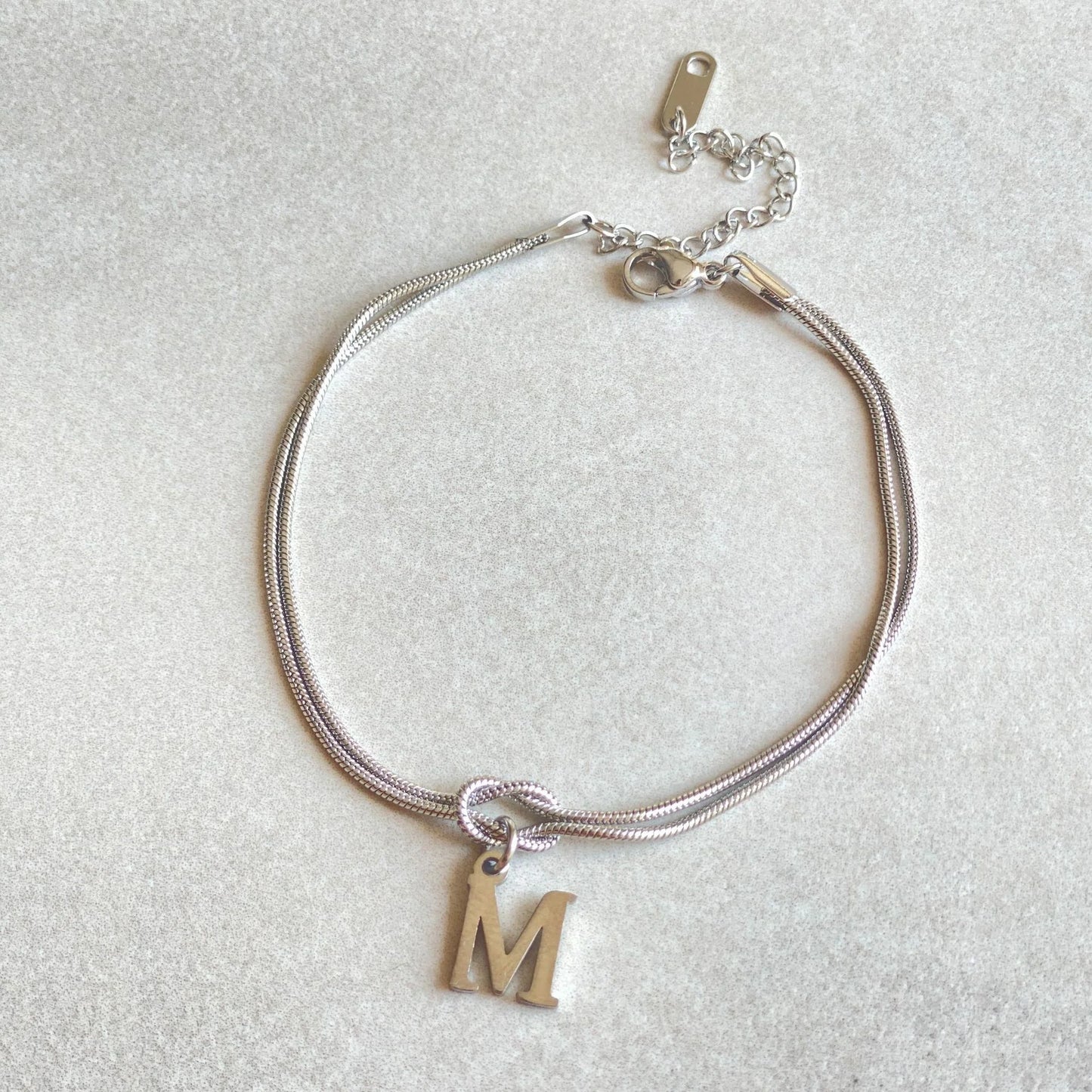 Elegant letter charm bracelets for women in gold and silver tones, featuring a delicate snake chain design and personalised letter charms.