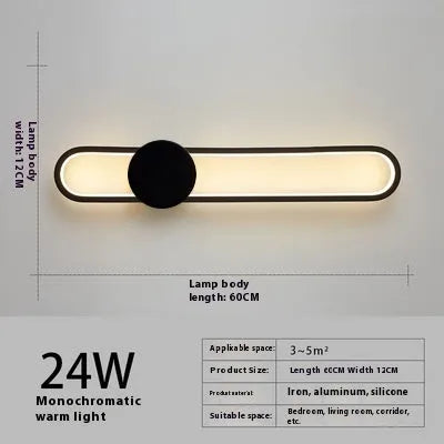 Modern black wall lamp with a long adjustable arm and round shade, mounted beside a bed.