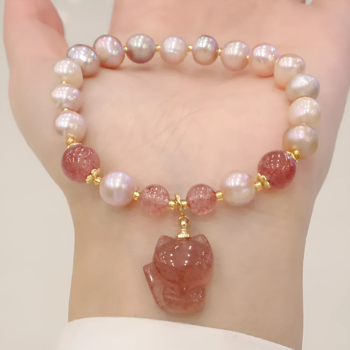Women's light pink freshwater pearl bracelet with strawberry quartz stones and fox charm