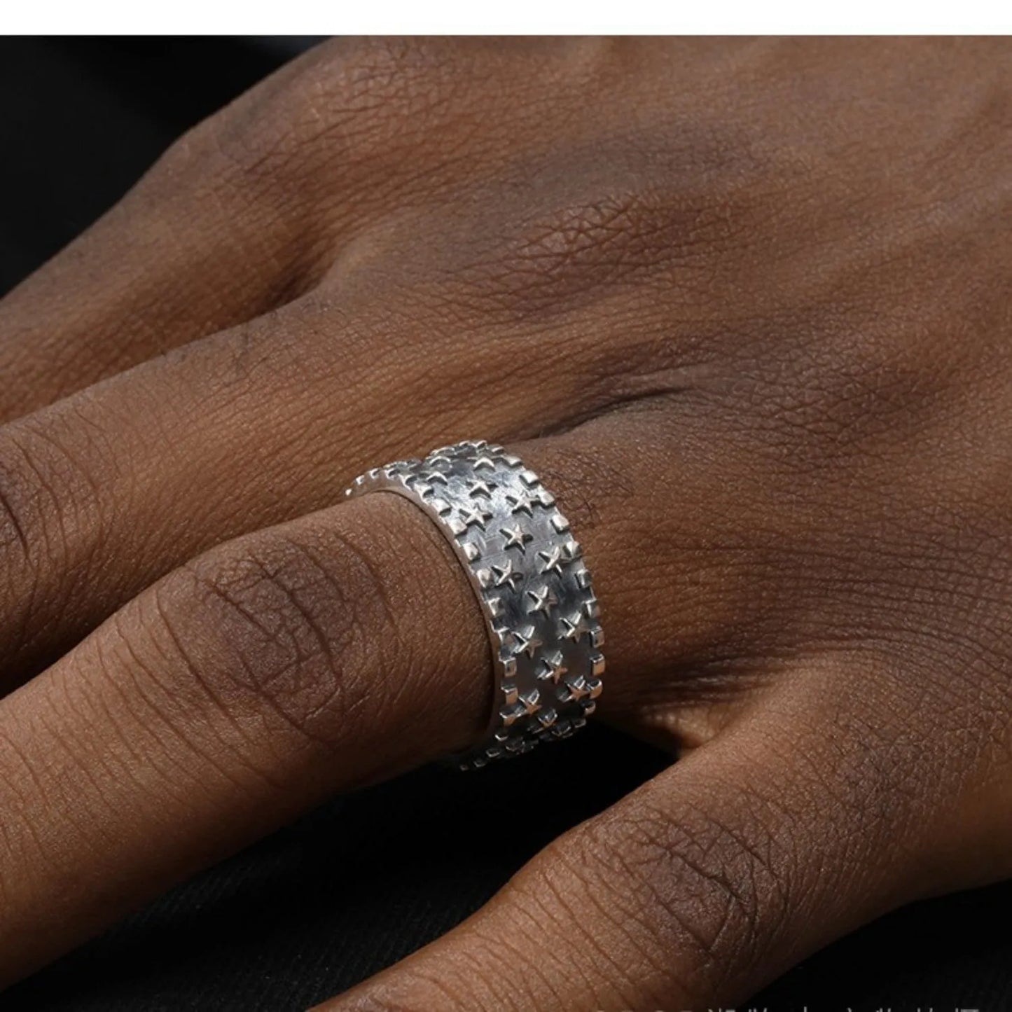 Adjustable sterling silver ring with a geometric pattern of multiple five-pointed stars on a polished band.