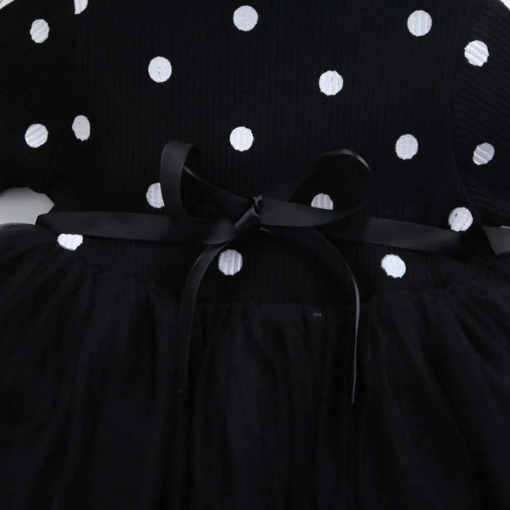 Baby girl wearing a long sleeve black tutu dress with lace detail for a birthday party.