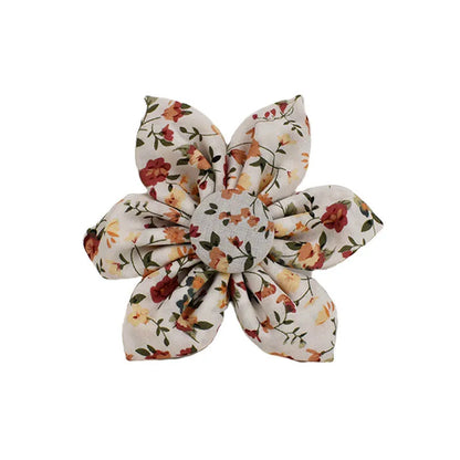 Small white flower decoration on a cloth dog collar and leash set with matching vest and bow.