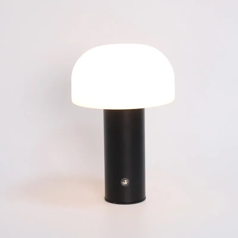 White USB table lamp with integrated charging port and UK plug on a wooden desk.