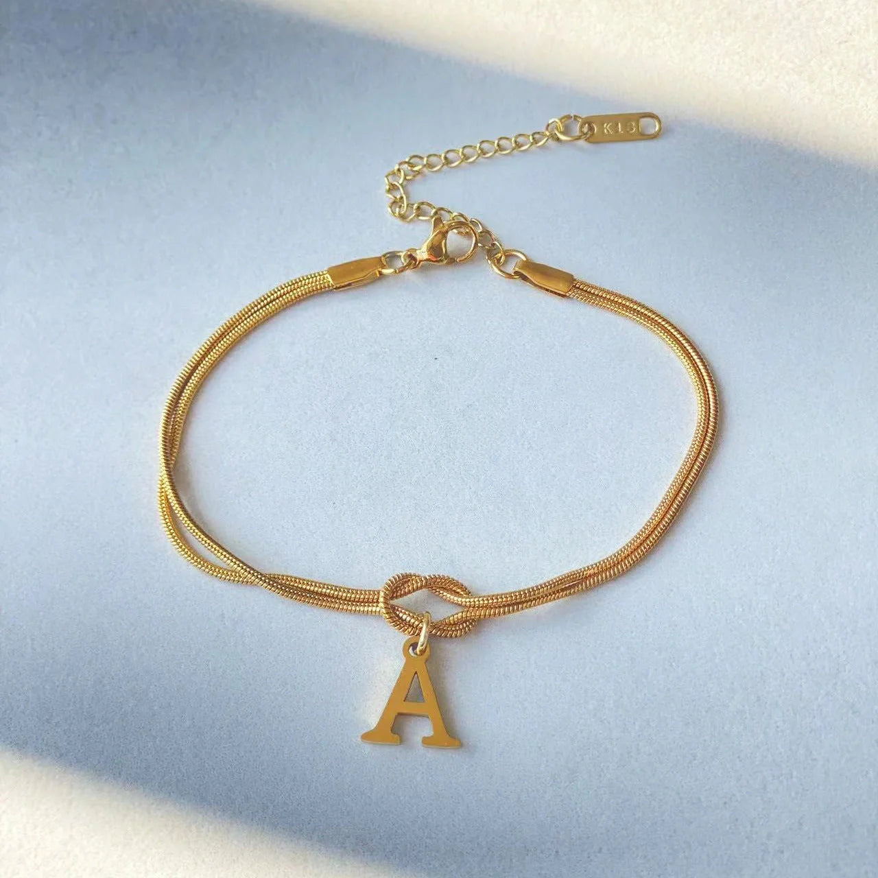 Elegant letter charm bracelets for women in gold and silver tones, featuring a delicate snake chain design and personalised letter charms.