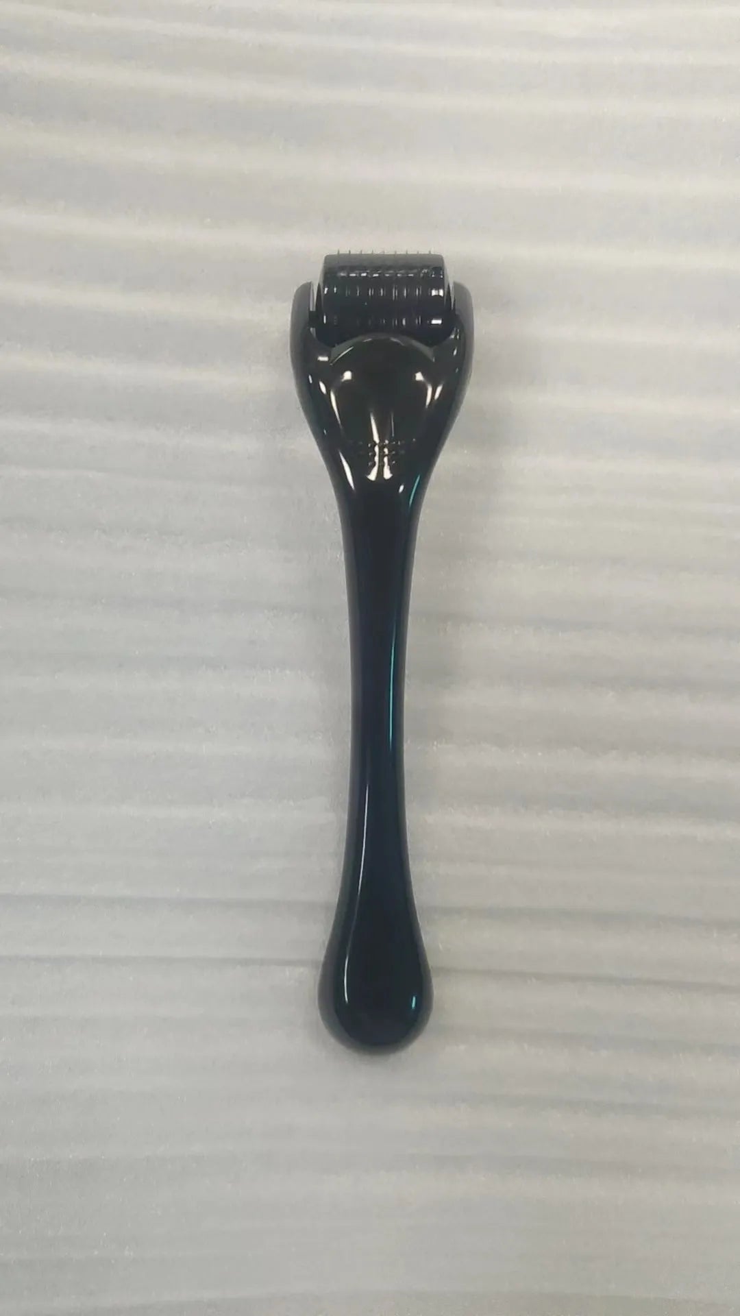 Sterile micro needle derma roller with black handle and coloured wheel on white background