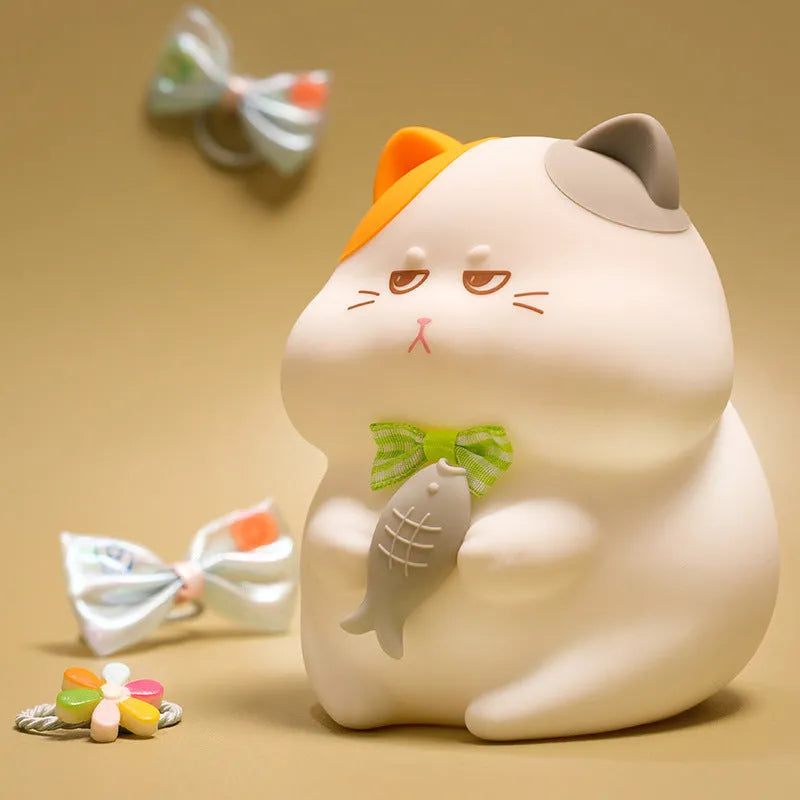 Yellow cartoon Greedy Cat desktop night light with plug, shown on a wooden desk.