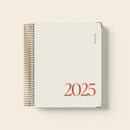 Cherry red A5 daily schedule coil notebook with spiral binding lying open.