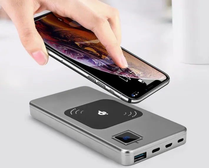 Slim black alloy power bank with LCD screen showing battery percentage, next to a smartphone.