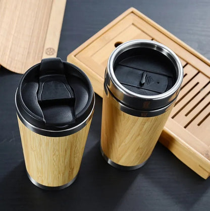 Natural bamboo fibre and stainless steel reusable travel coffee cup with black leak-proof lid on a table