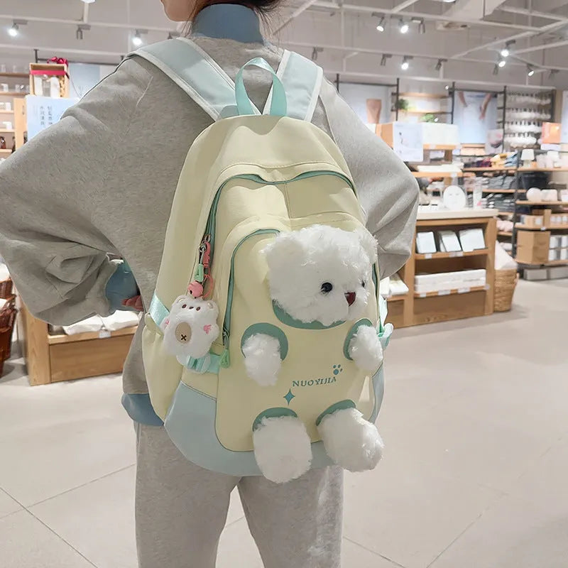 Macaron colour nylon school backpack with curved straps, shown in yellow pink, with a pendant attached.