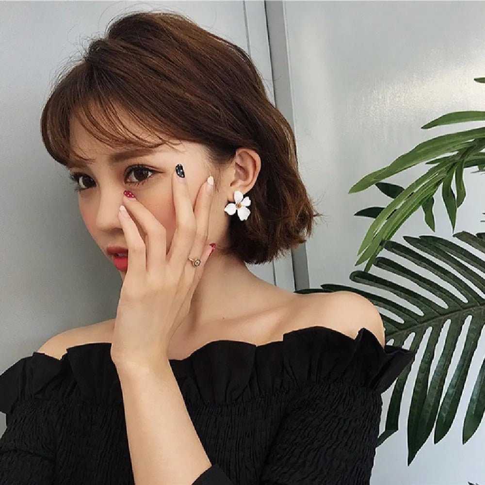 A pair of women's flower-shaped alloy stud earrings with a white electroplated finish.
