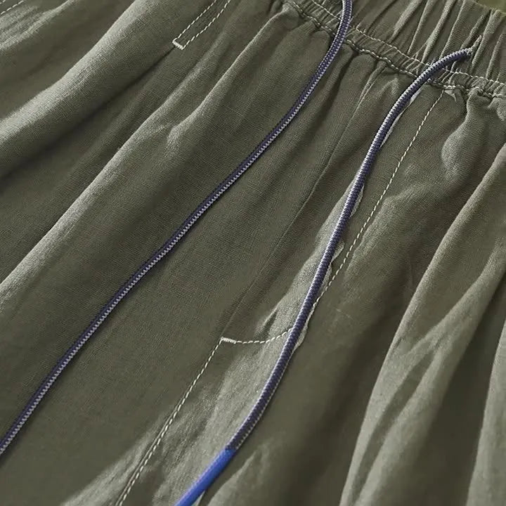 Men's linen shorts in a loose straight drooping fit for summer casual wear, available in green and black with mid-waist drawstring closure, sizes M to 3XL with thin lightweight fabric suitable for daily and work scenarios.