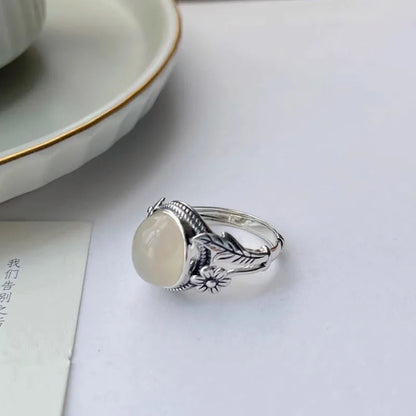 Adjustable open-mouth copper vintage ring with U-shape and antiqued white chalcedony-style finish on a wooden surface.