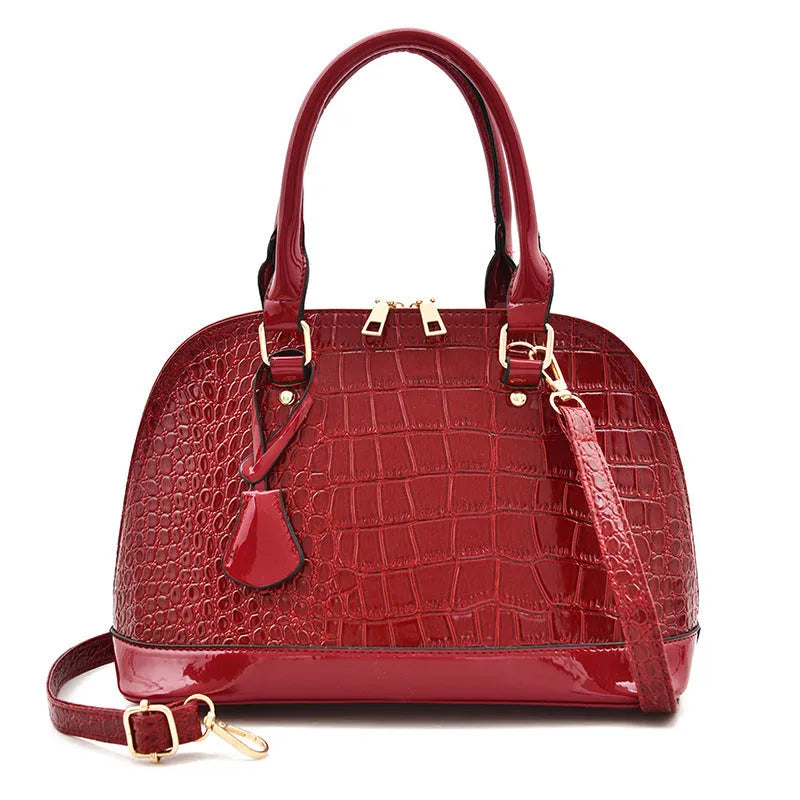 Large shiny black PU leather crossbody bag with a shell shape, shown from the front.