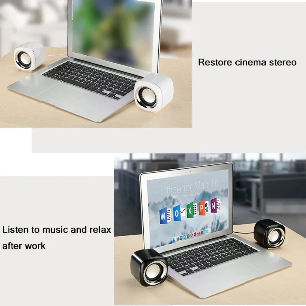 A pair of small black or white cube-shaped wired computer speakers with a 3.5mm audio plug on a desk.