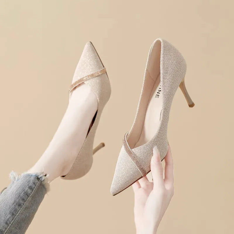 Gold women's stiletto high heels with pointed toe on a plain background.