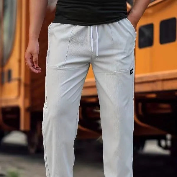 Men's light grey polyester trousers with an elasticated waistband laid flat