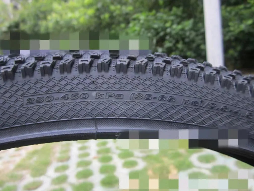 Mountain bike tyre with black tread and sidewall, showing size options like 26x1.95 and 29x2.1 inches for off-road cycling.
