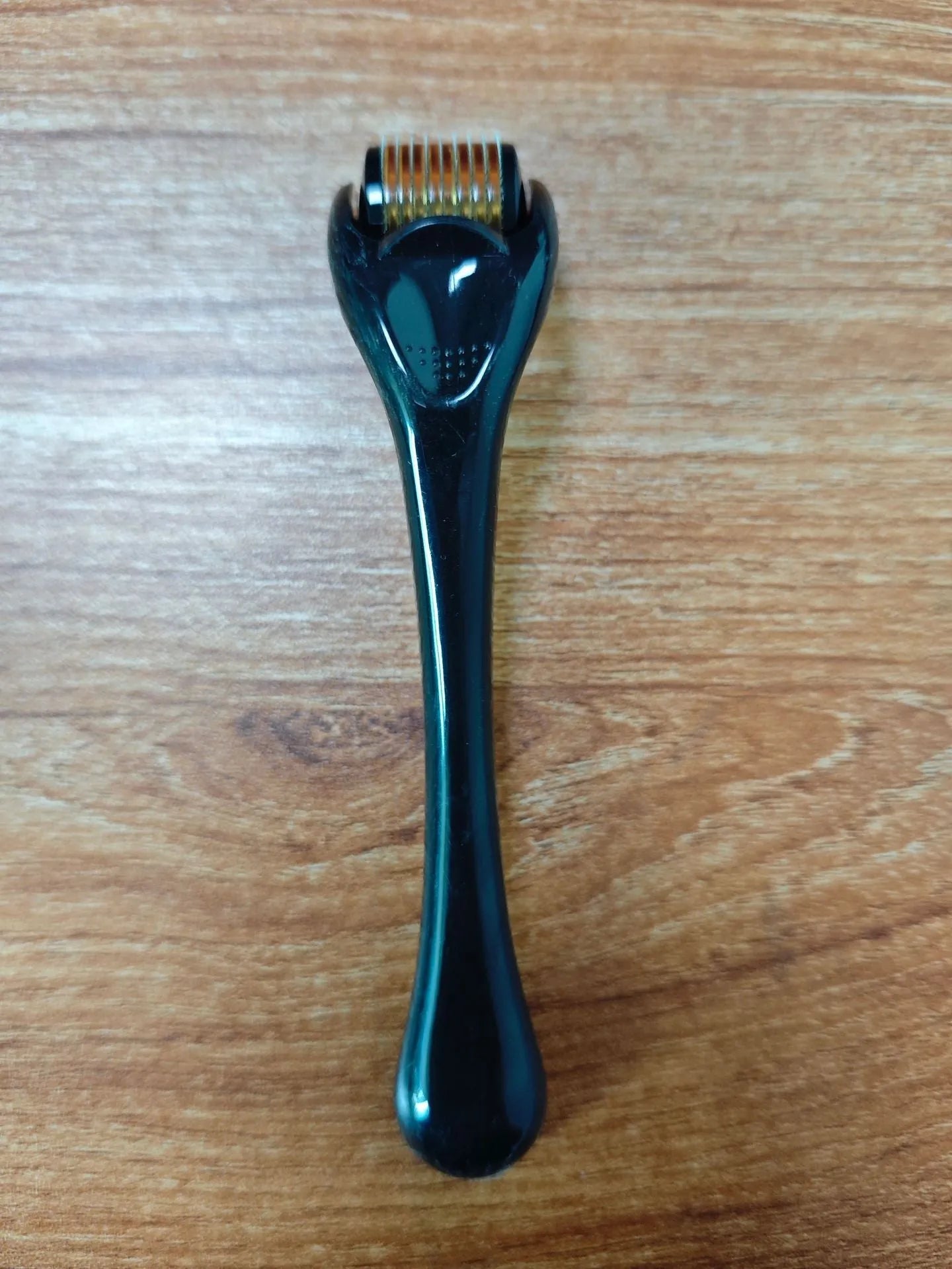 Sterile micro needle derma roller with black handle and coloured wheel on white background