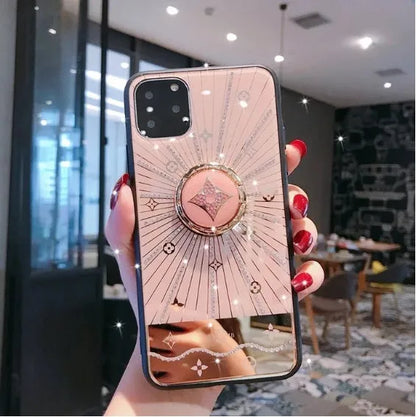 Luxury diamond and gold ring stand attached to the back of an iPhone in rose gold colour.