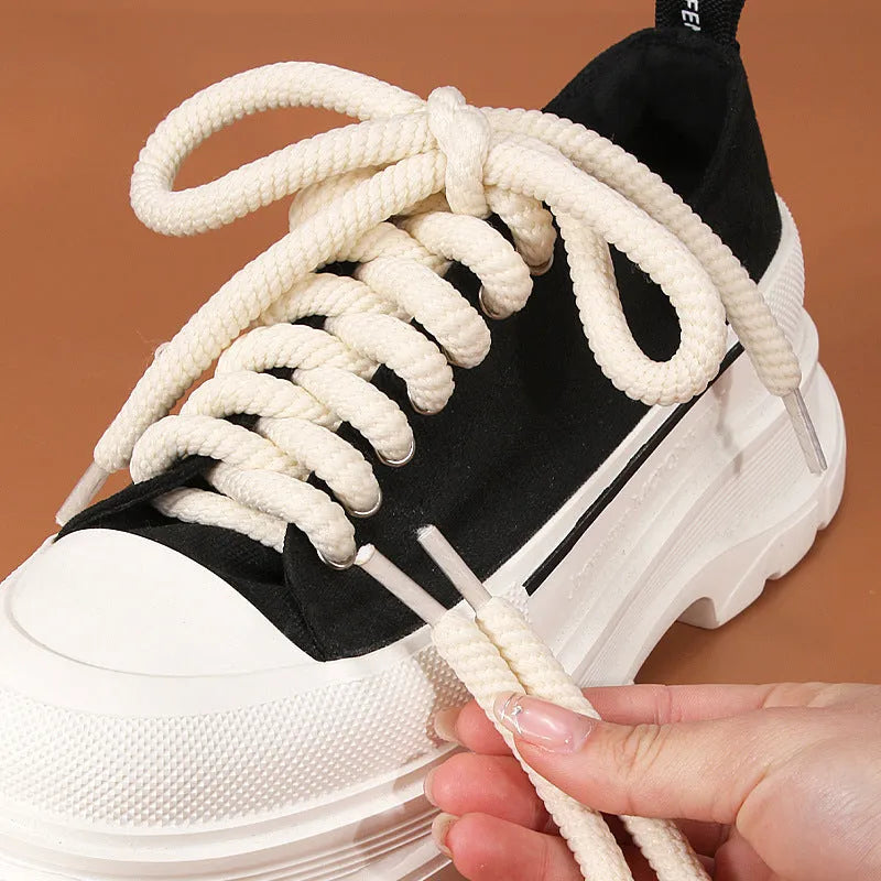 Round woven white, beige, and black shoelaces for bread shoes showing different lengths on a flat surface.