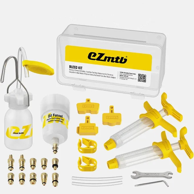 Bicycle hydraulic disc brake oil bleed kit tools with syringes, adapters, and wrenches on a workbench