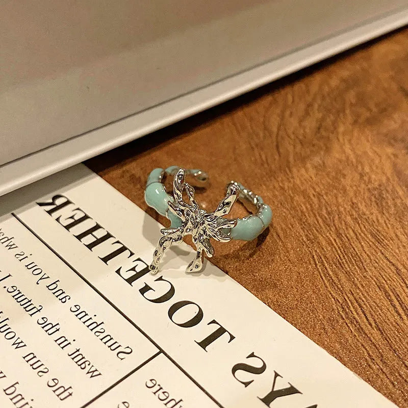 Copper butterfly women's ring with an open loop design on a plain background.