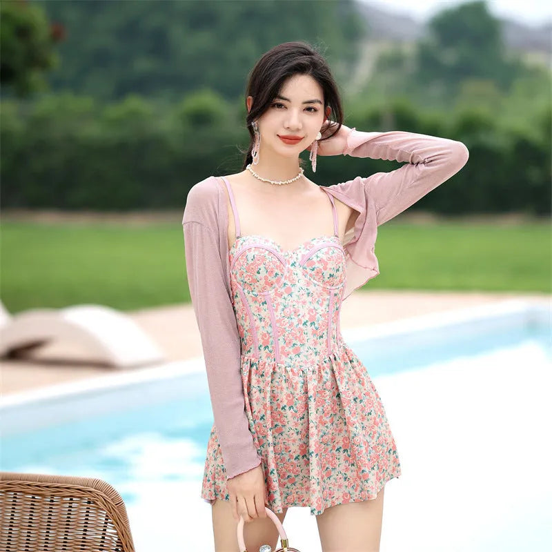 Women's pink floral one-piece jumpsuit swimsuit with suspender straps on a hanger.
