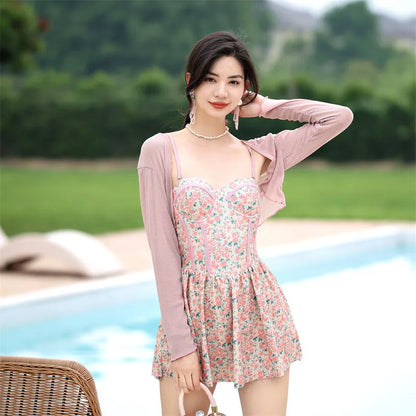 Women's pink floral one-piece jumpsuit swimsuit with suspender straps on a hanger.