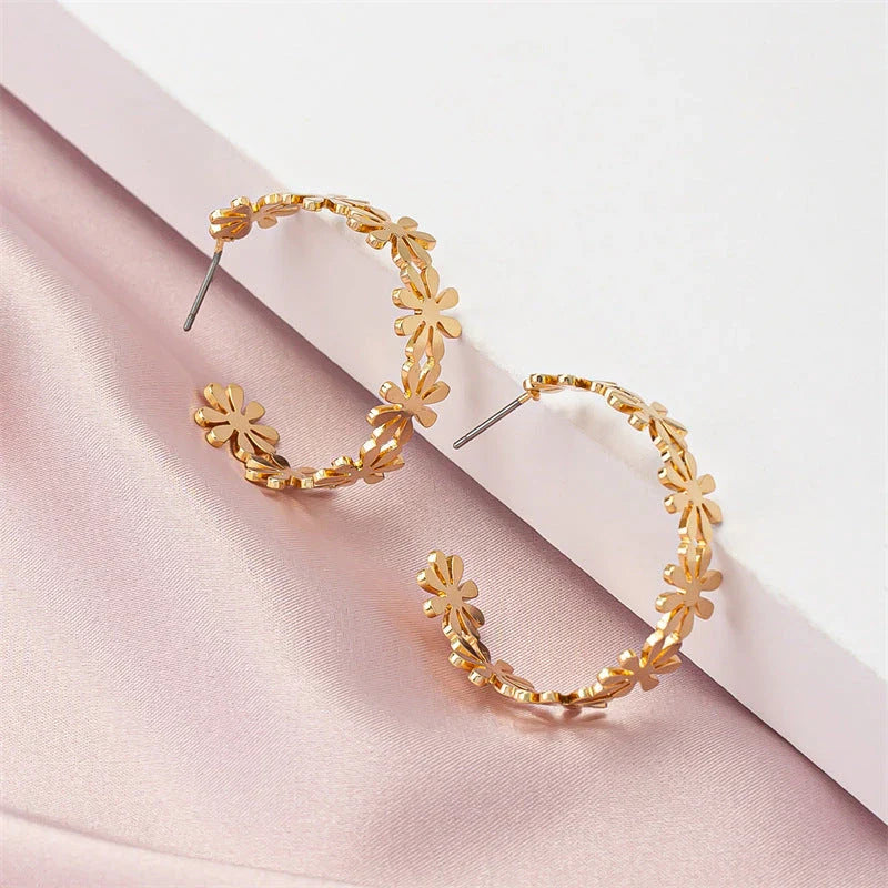 Pair of golden geometric C-shaped flower drop earrings with a vintage-inspired design