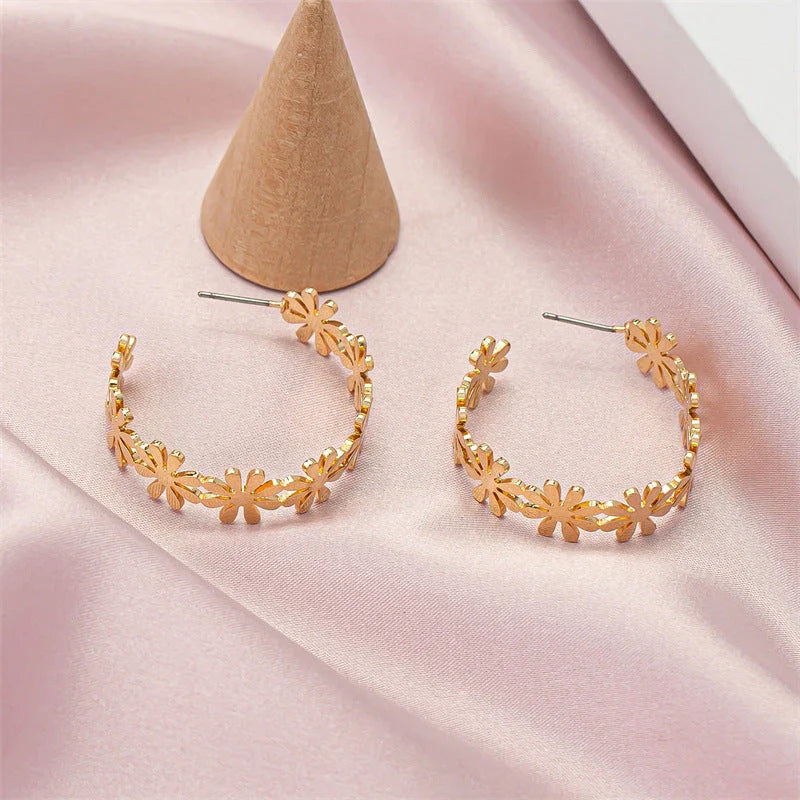 Pair of golden geometric C-shaped flower drop earrings with a vintage-inspired design