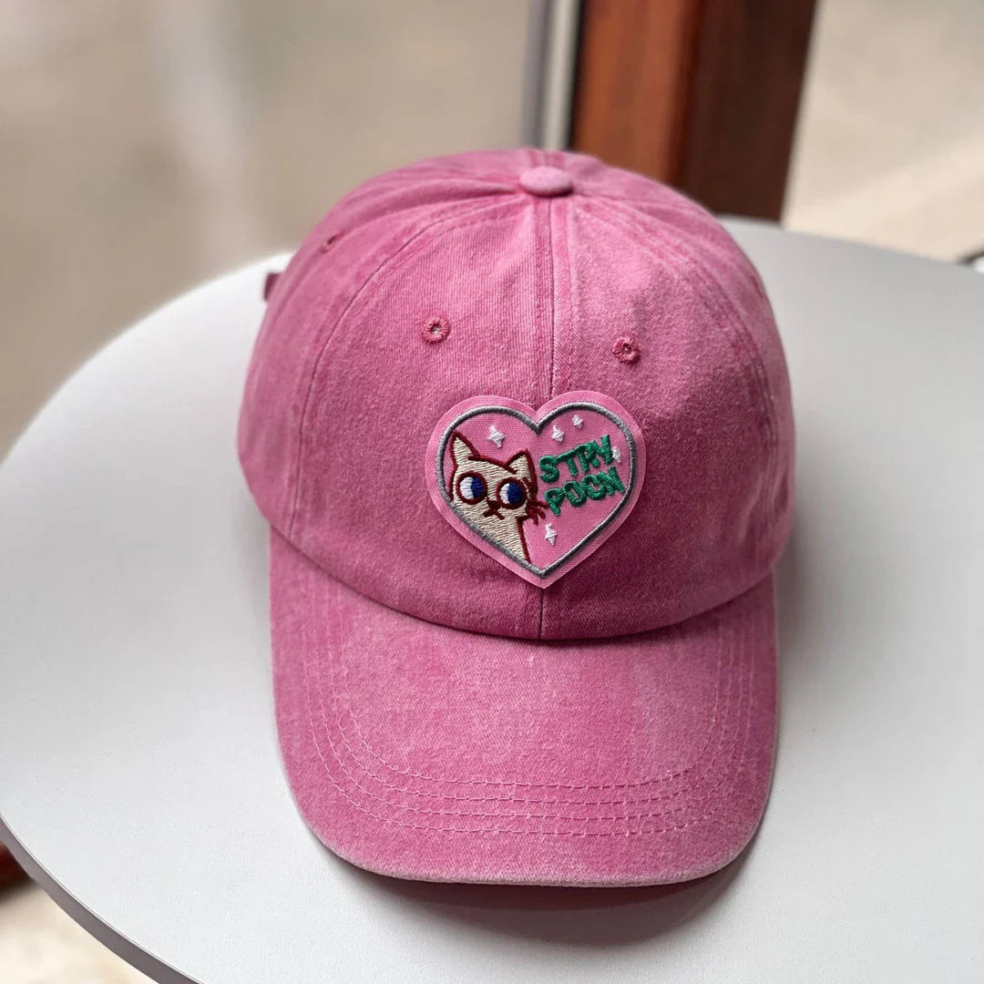 Two pink baseball caps featuring a cartoon love design, perfect for casual and festival wear