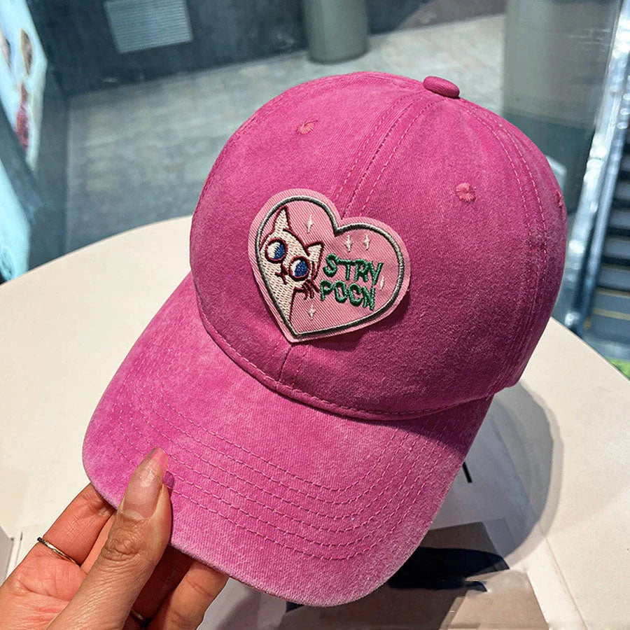 Two pink baseball caps featuring a cartoon love design, perfect for casual and festival wear