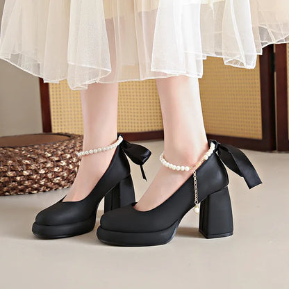 Women's beige preppy style Mary Jane shoes with chunky heel, ankle strap buckle, and pearl detail.
