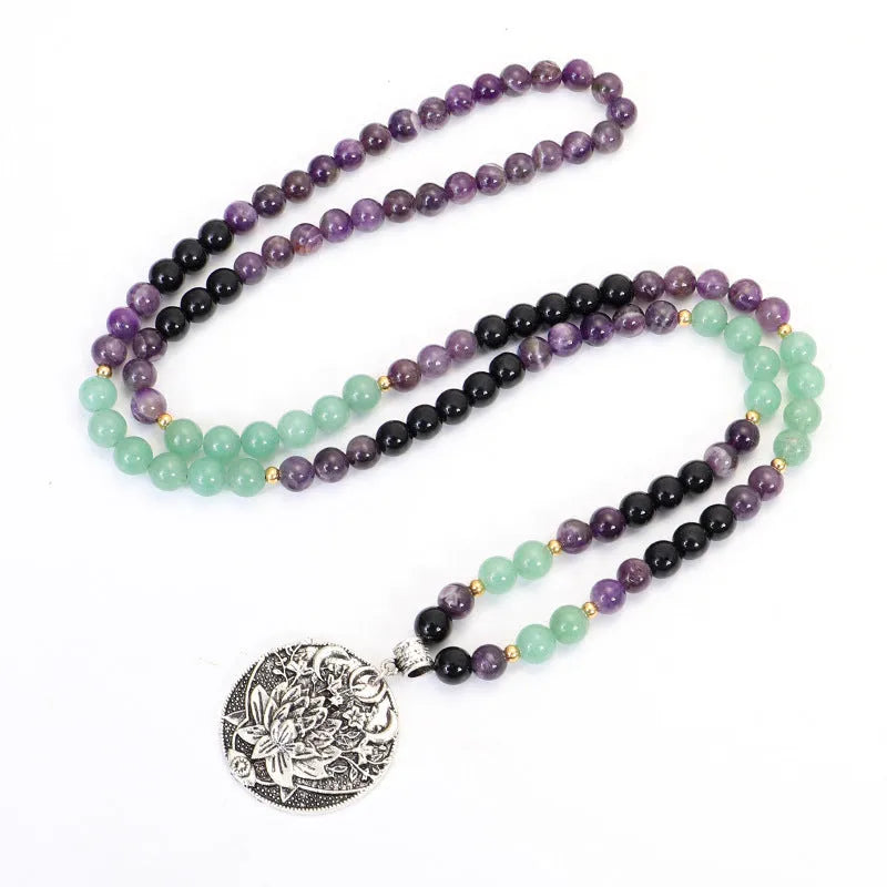 Long stone bead necklace with alloy lotus pendant and matching bracelet set on a background.
