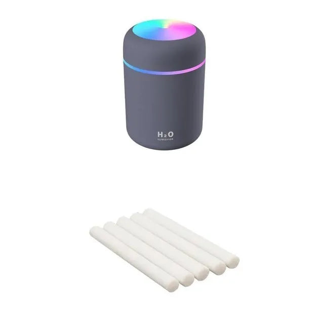 Pink USB desktop humidifier with LED lights and water tank on wooden desk