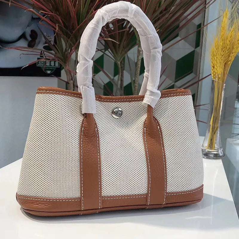 Canvas and leather tote bag in bucket shape with crossbody strap, shown in black, brown, gray or red colour options