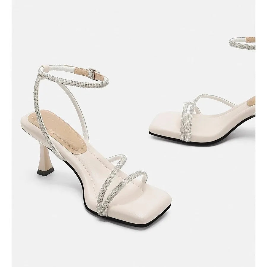 Women's silver rhinestone sandals with square toe and ankle strap buckle on a white background.
