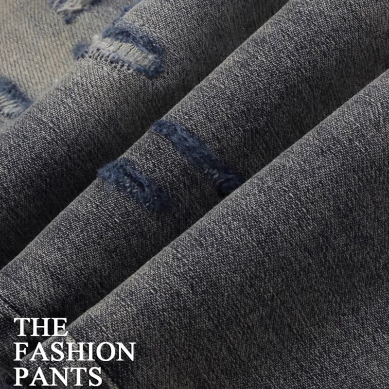 Men's slim fit cotton jeans with washed-out finish, hole patch detailing, and embroidery in old colour