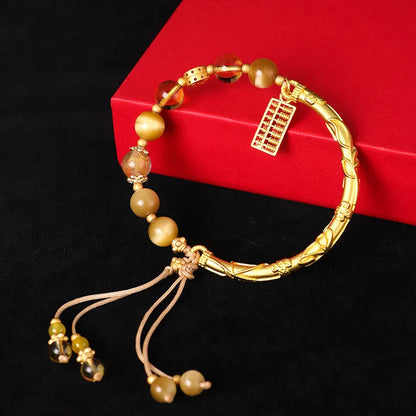 Women's handmade beaded bracelet with diamond-shaped tigereye and citrine abacus tag, yellow tower crystals, and copper details.
