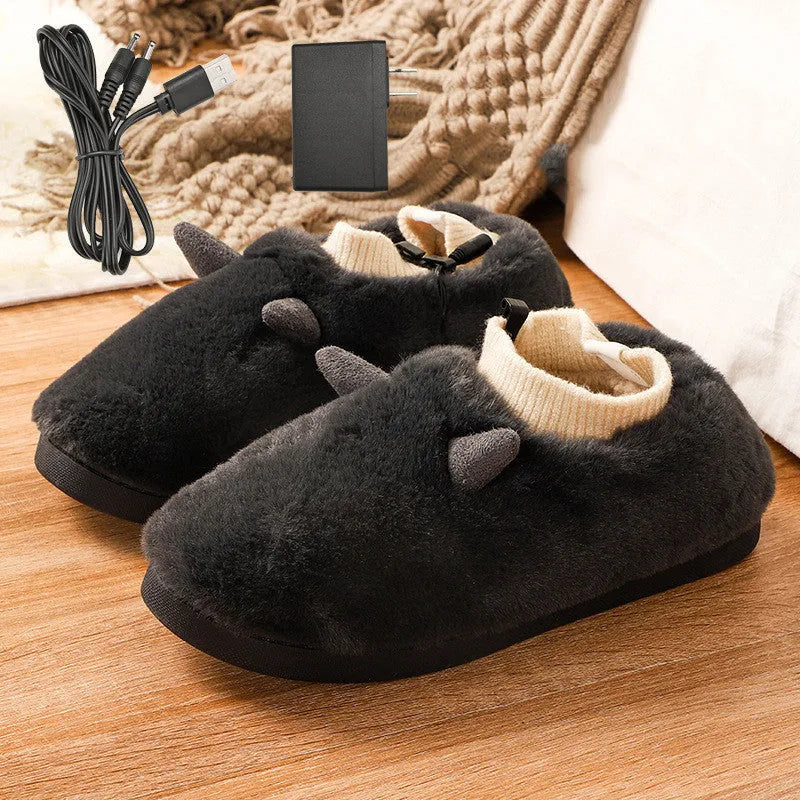 USB heating slippers in black plugged into a laptop, showing the cable and soft velvet upper.