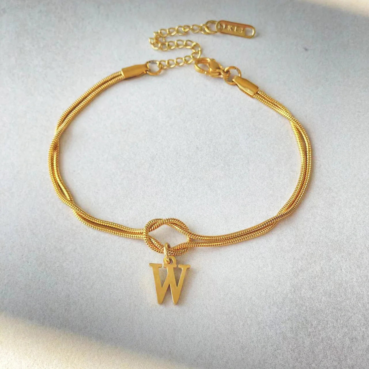 Elegant letter charm bracelets for women in gold and silver tones, featuring a delicate snake chain design and personalised letter charms.