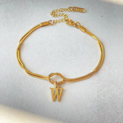 Elegant letter charm bracelets for women in gold and silver tones, featuring a delicate snake chain design and personalised letter charms.