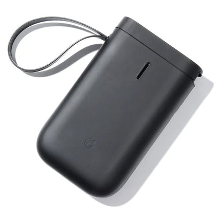 D11 black Bluetooth thermal label printer on a desk next to a smartphone showing the label design app